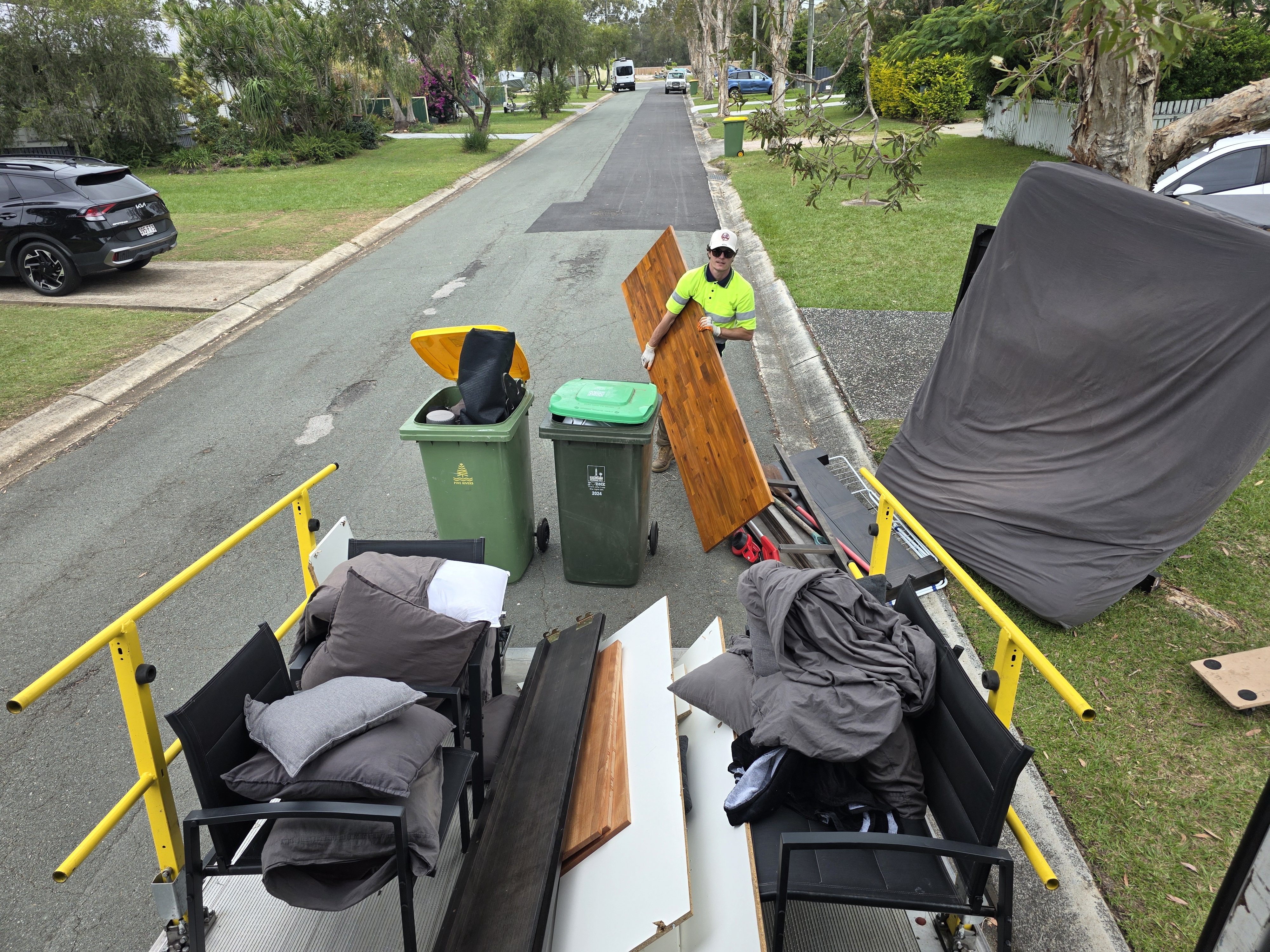 Crew loading a residential rubbish removal truck in a Brisbane driveway